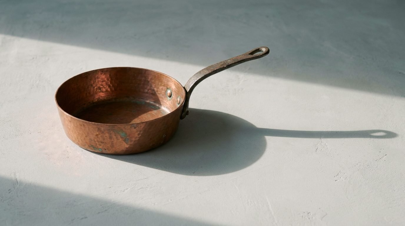 A hammered copper pan with an iron handle, in low afternoon light